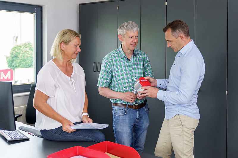 Drei MBA Mitarbeiter mit MBA800 in der Hand im Gespräch